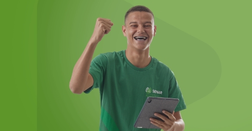 Homem negro e jovem de camiseta verde sorrindo, de braço levantado comemorando