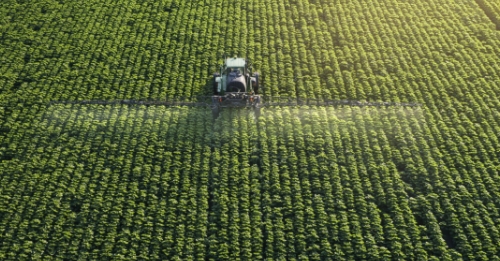Imagem aérea de uma plantação agrícola com máquina em ação